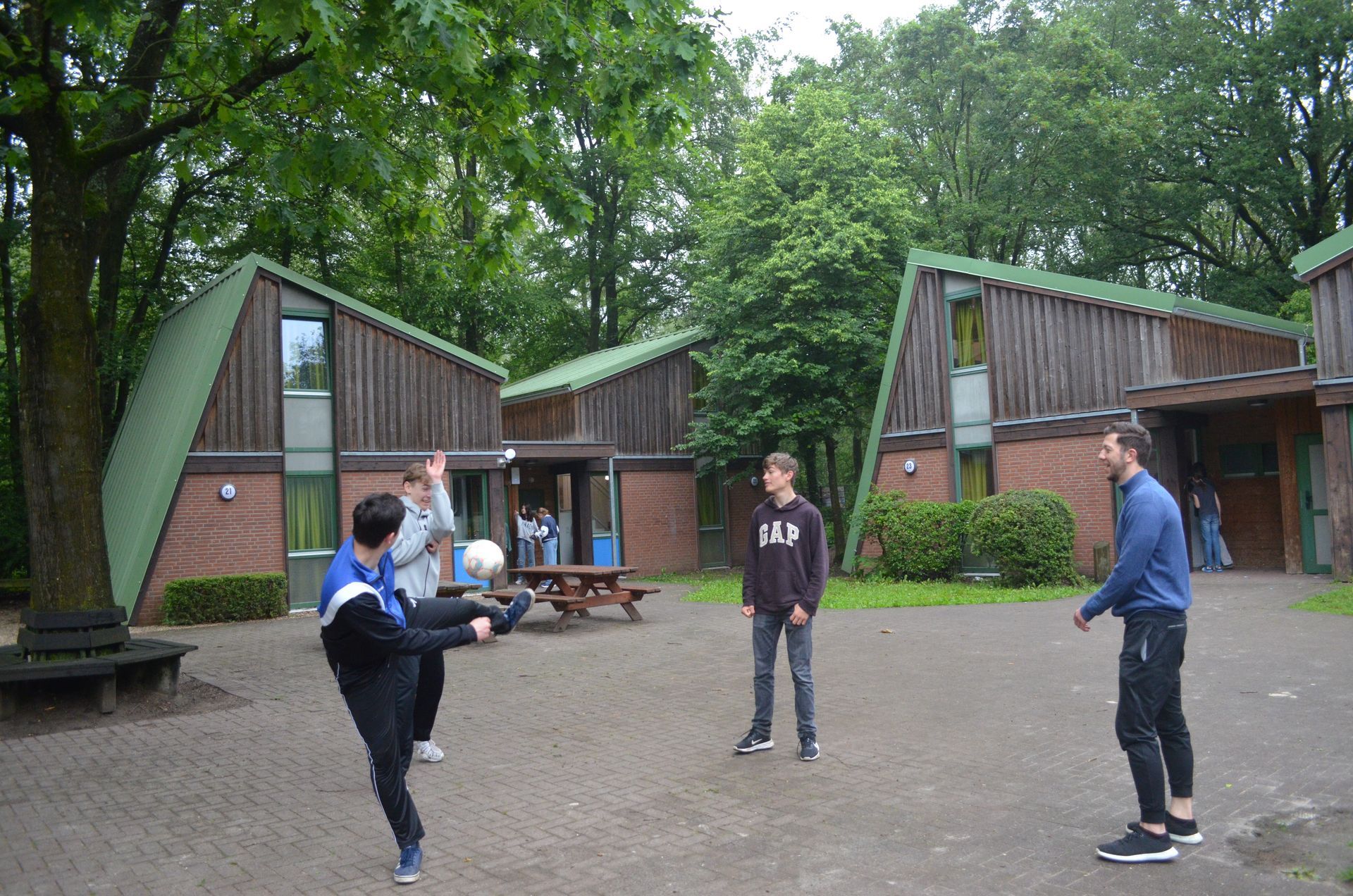 Eine Gruppe junger Männer spielt vor einem Gebäude Fußball  - Karate-Freizeit.