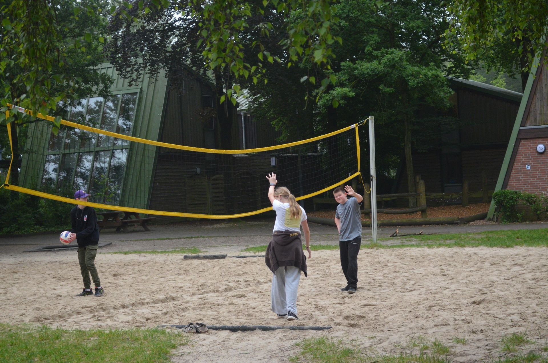 Eine Gruppe von Leuten spielt Volleyball auf einem Sandplatz  - Karate-Freizeit.