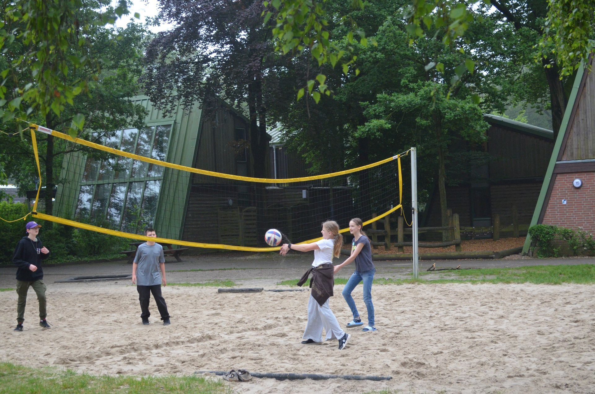 Eine Gruppe von Leuten spielt Volleyball im Sand - Karate-Jugendfreizeit.