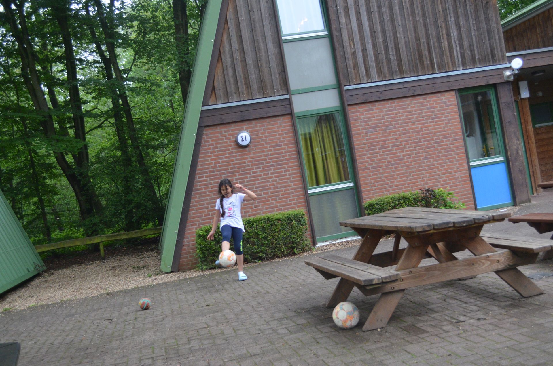 Ein Mädchen kickt vor einem Picknicktisch einen Fußball - Karate-Jugendfreizeit.