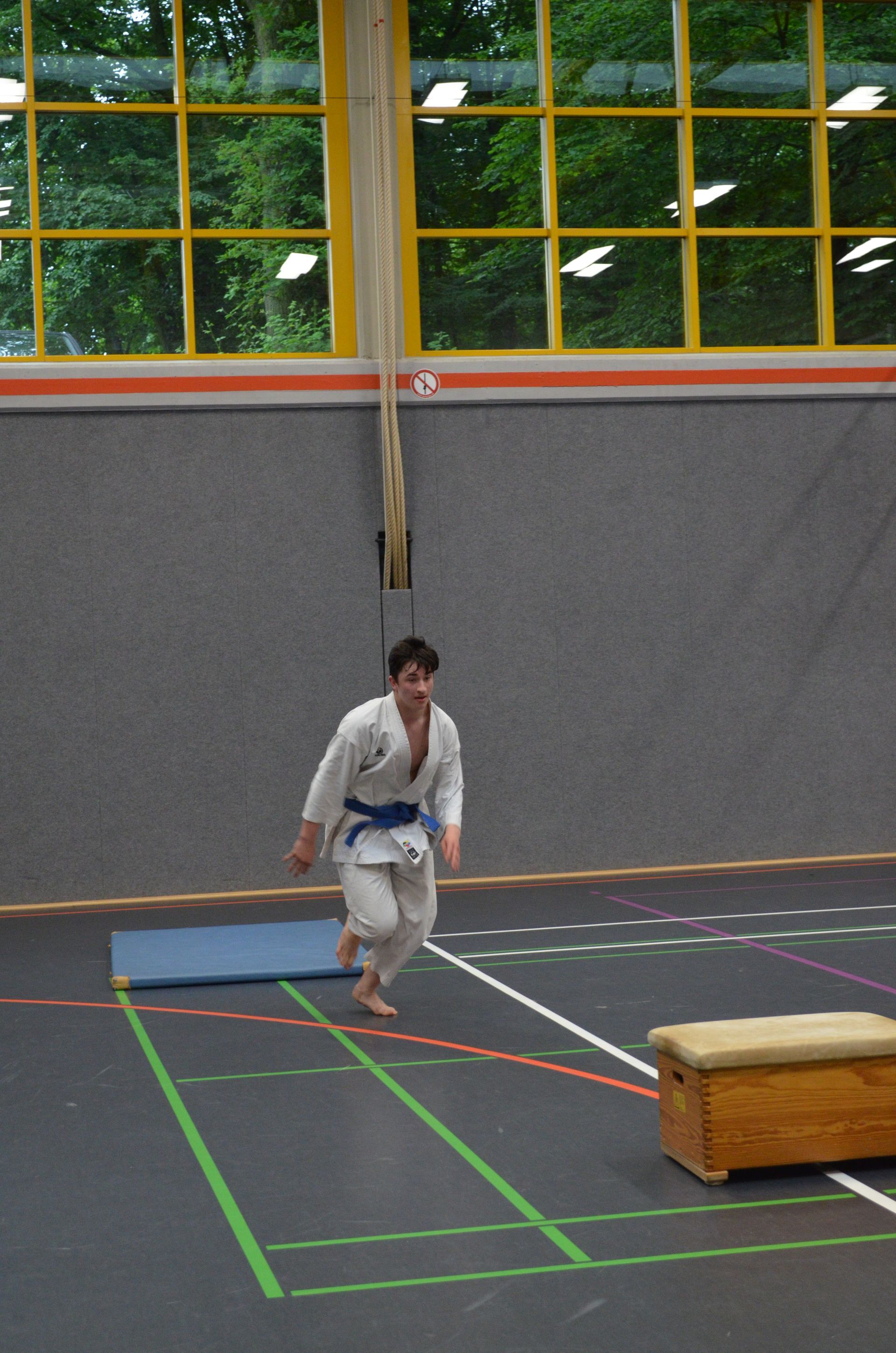 Ein Mann in einer weißen Karateuniform springt in einem Fitnessstudio - Karate-Jugendfreizeit.