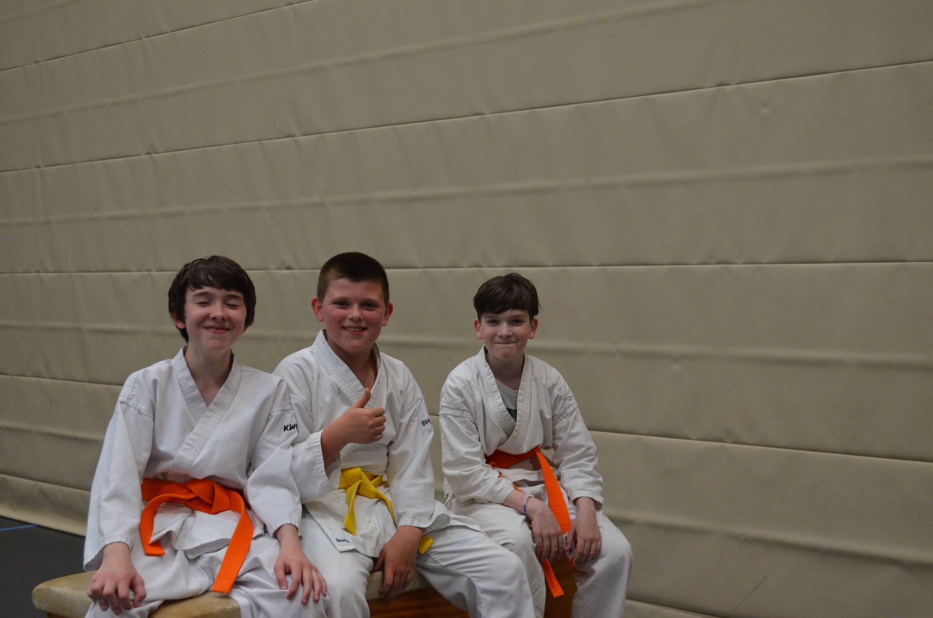 Drei junge Jungen in Karateuniformen sitzen auf einer Bank - Karate-Jugendfreizeit.