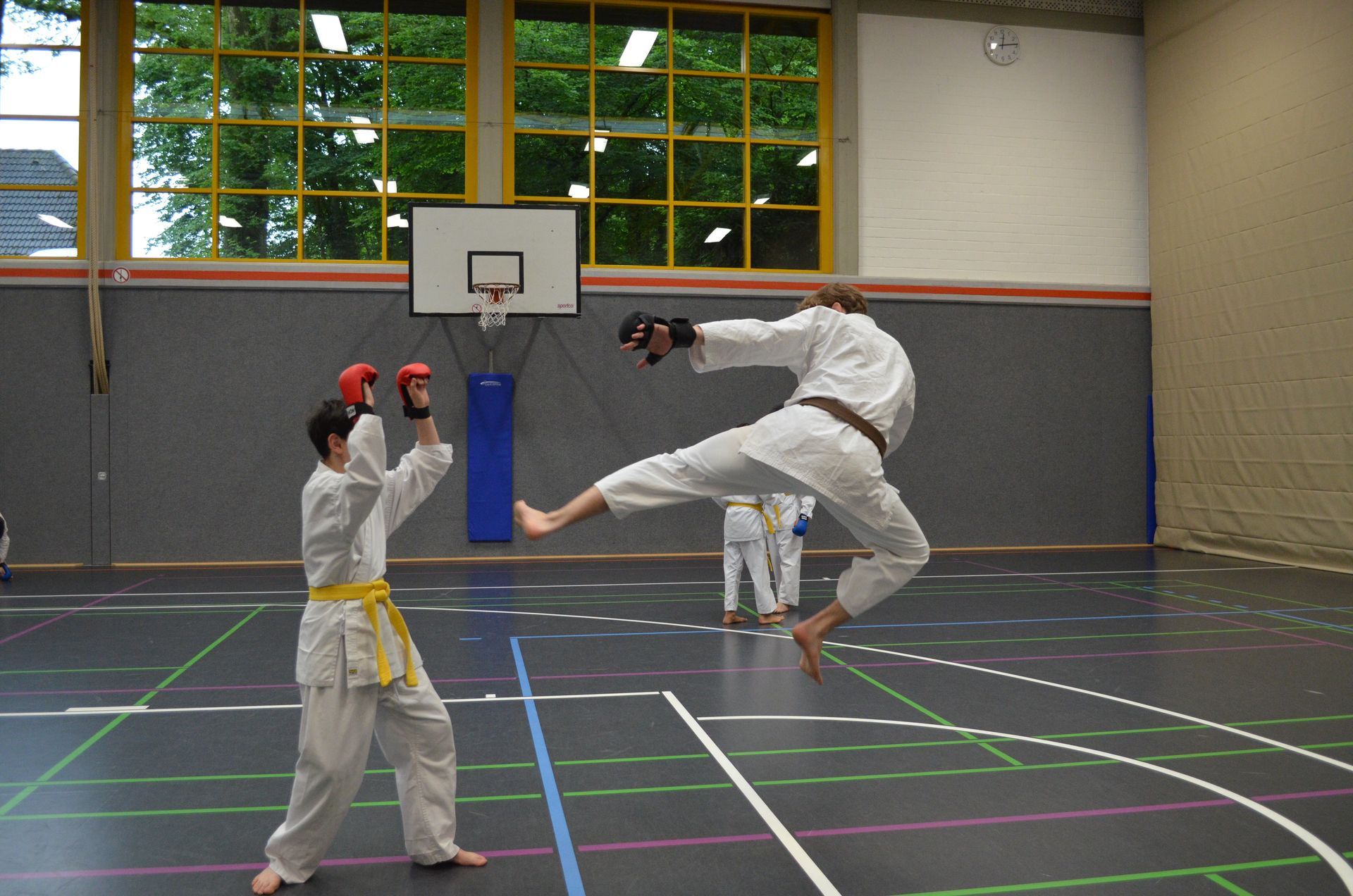 Zwei Männer üben Kampfsport in einem Fitnessstudio mit einem Basketballkorb im Hintergrund - Karate-Jugendfreizeit.