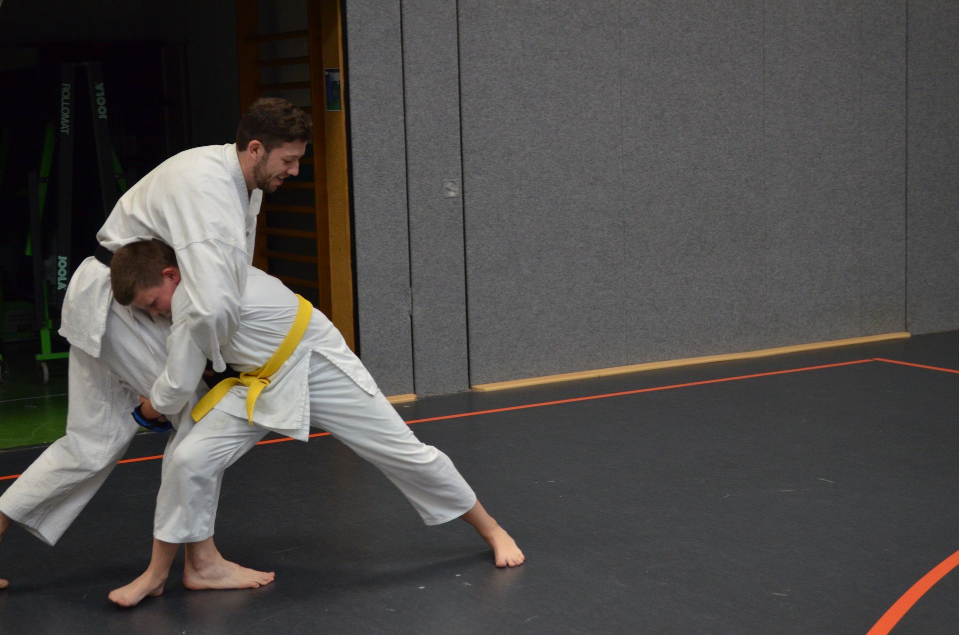 Zwei Männer trainieren in einem Fitnessstudio Judo und einer hat einen gelben Gürtel - Karate-Jugendfreizeit.