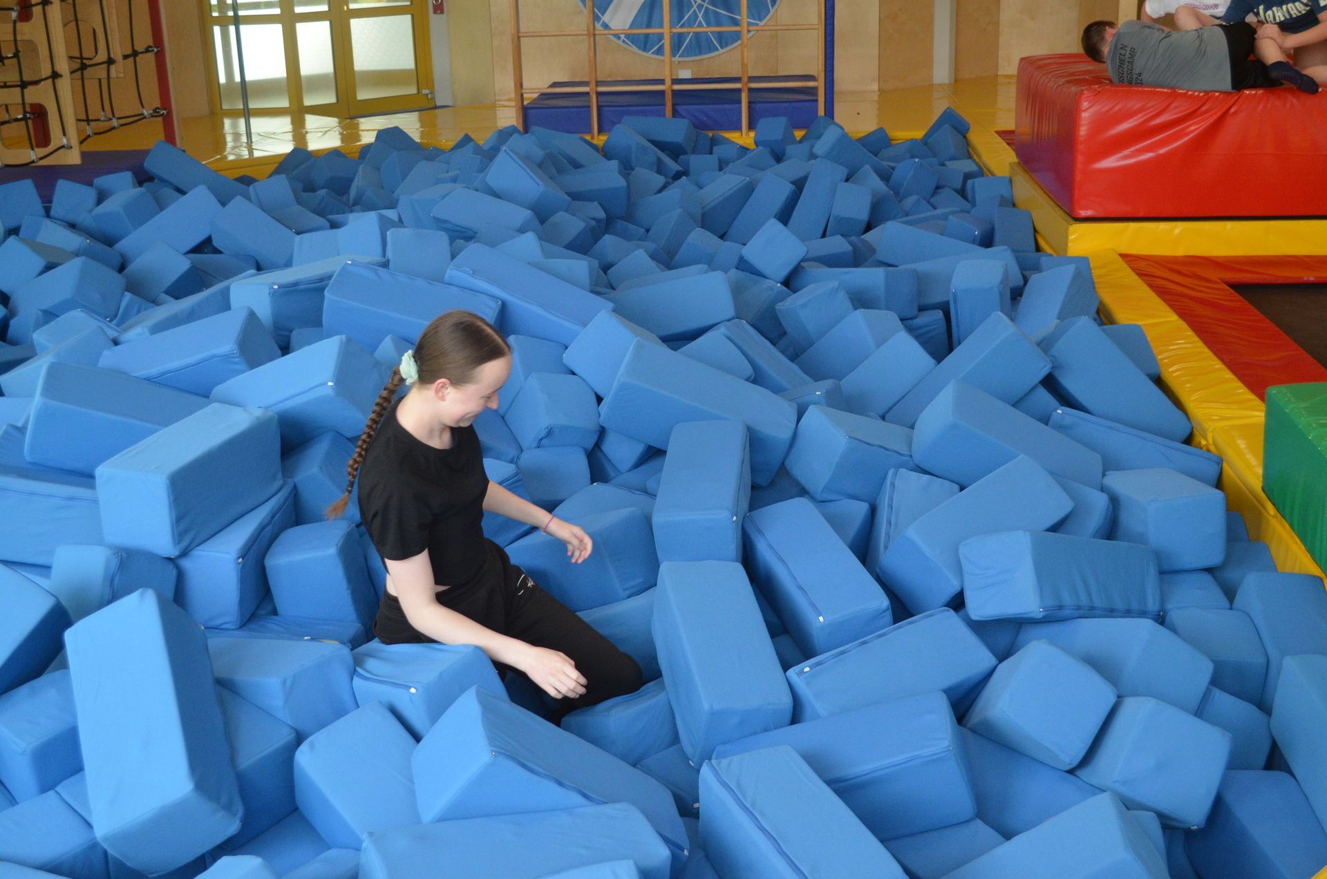 Eine Frau sitzt in einem Stapel blauer Schaumstoffblöcke - Karate-Jugendfreizeit.