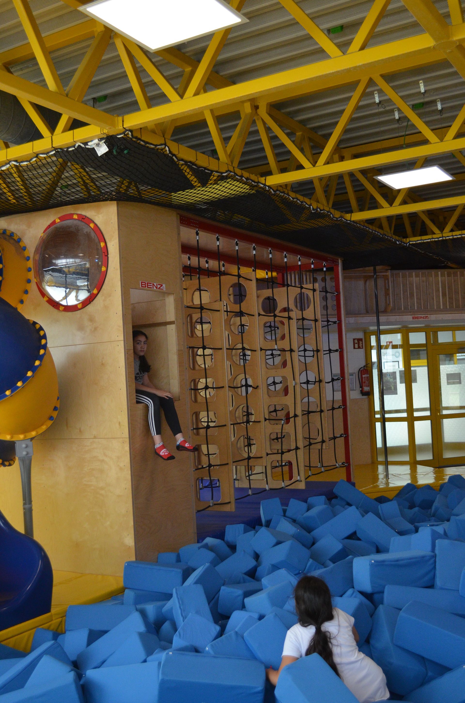 Ein Mädchen sitzt in einem Stapel blauer Schaumstoffblöcke - Karate-Jugendfreizeit.