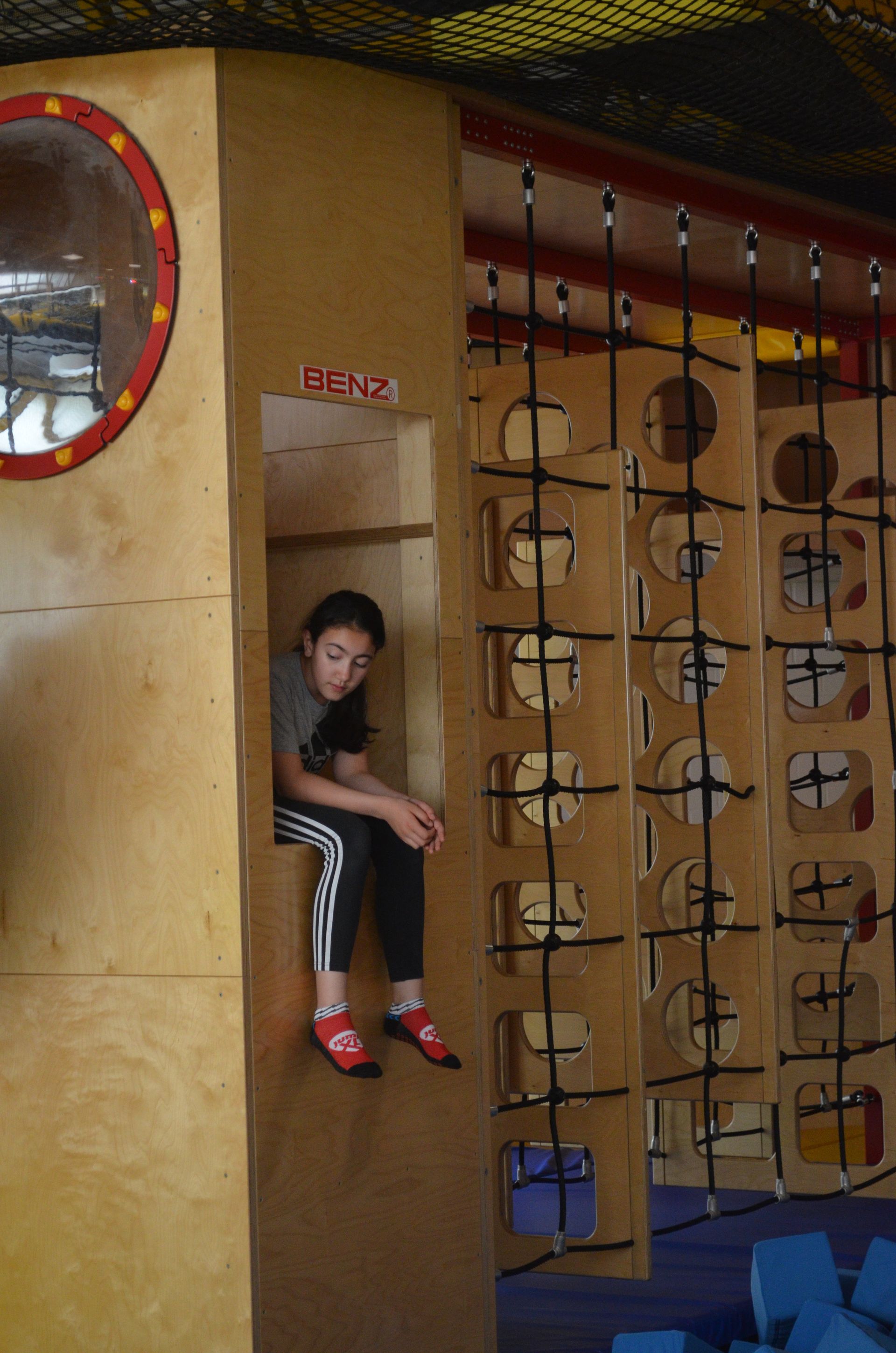 Ein kleines Mädchen sitzt auf einer Holzmauer auf einem Spielplatz - Karate-Jugendfreizeit.