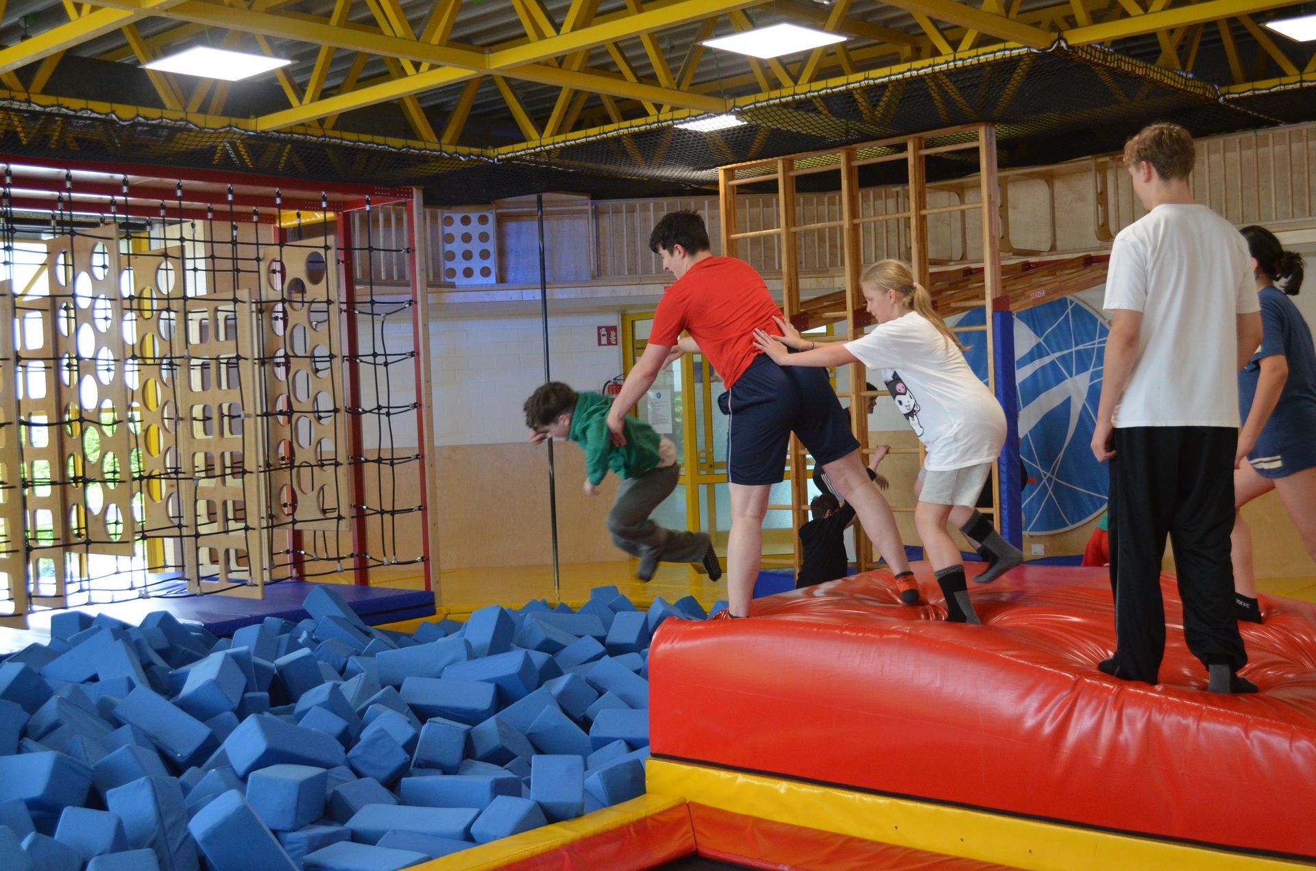 Eine Gruppe Kinder spielt in einer Turnhalle auf einem Trampolin - Karate-Jugendfreizeit.