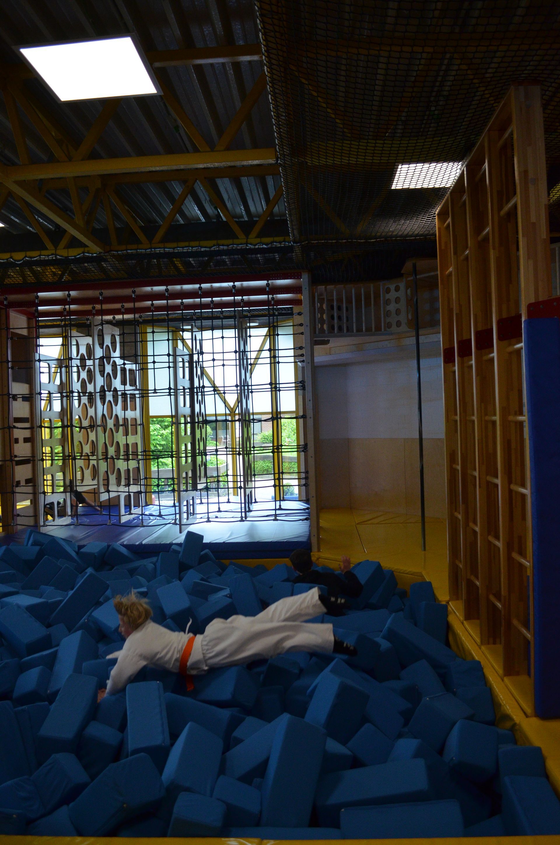 Eine Person liegt in einer Turnhalle auf einem Stapel blauer Blöcke - Karate-Jugendfreizeit.