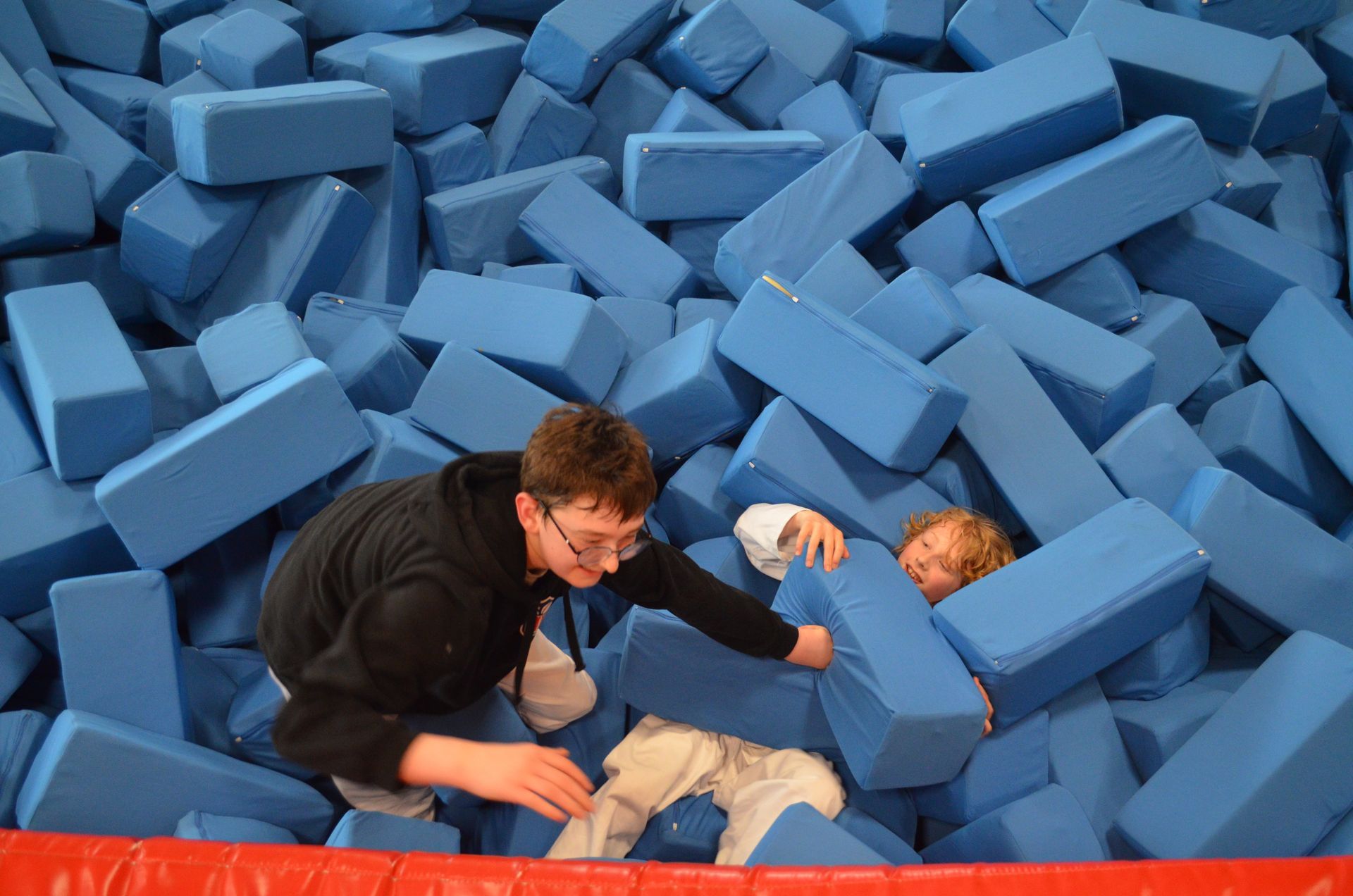 Zwei Kinder spielen in einem Stapel blauer Schaumstoffblöcke - Karate-Jugendfreizeit.