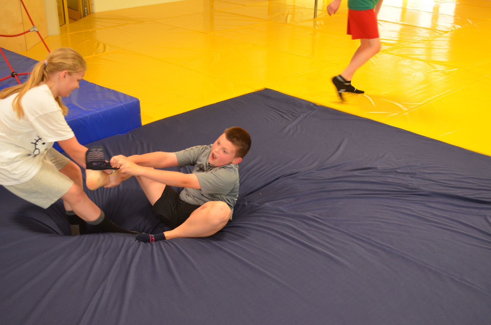 Ein Mädchen hilft einem Jungen beim Ringen auf einer Matte - Karate-Jugendfreizeit.