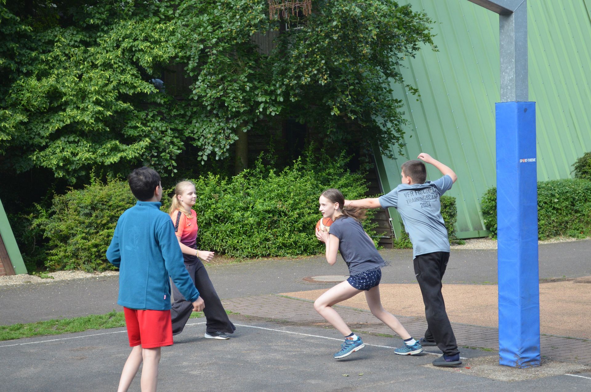 Eine Gruppe Kinder spielt auf einem Platz Basketball - Karate-Jugendfreizeit.