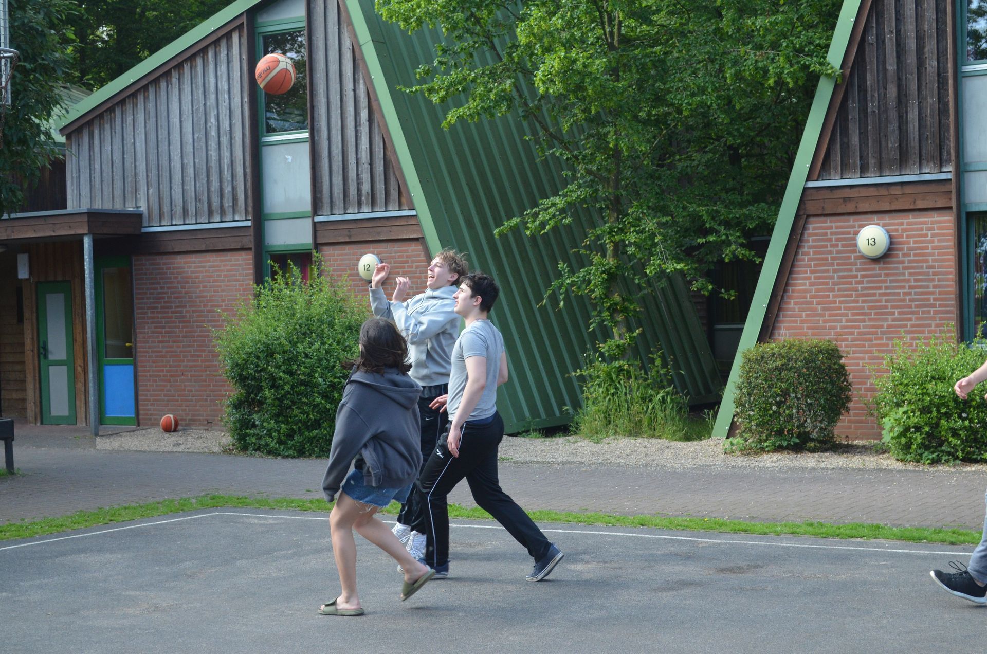 Eine Gruppe von Leuten spielt vor einem Gebäude Basketball - Karate-Jugendfreizeit.
