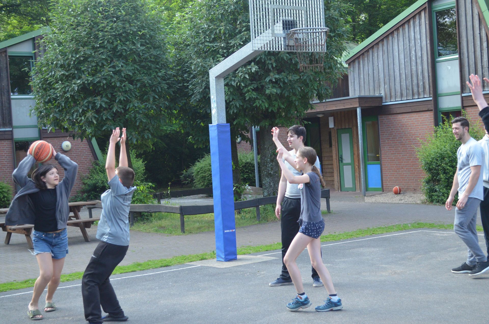 Eine Gruppe von Leuten spielt Basketball auf einem Platz- Karate-Jugendfreizeit.