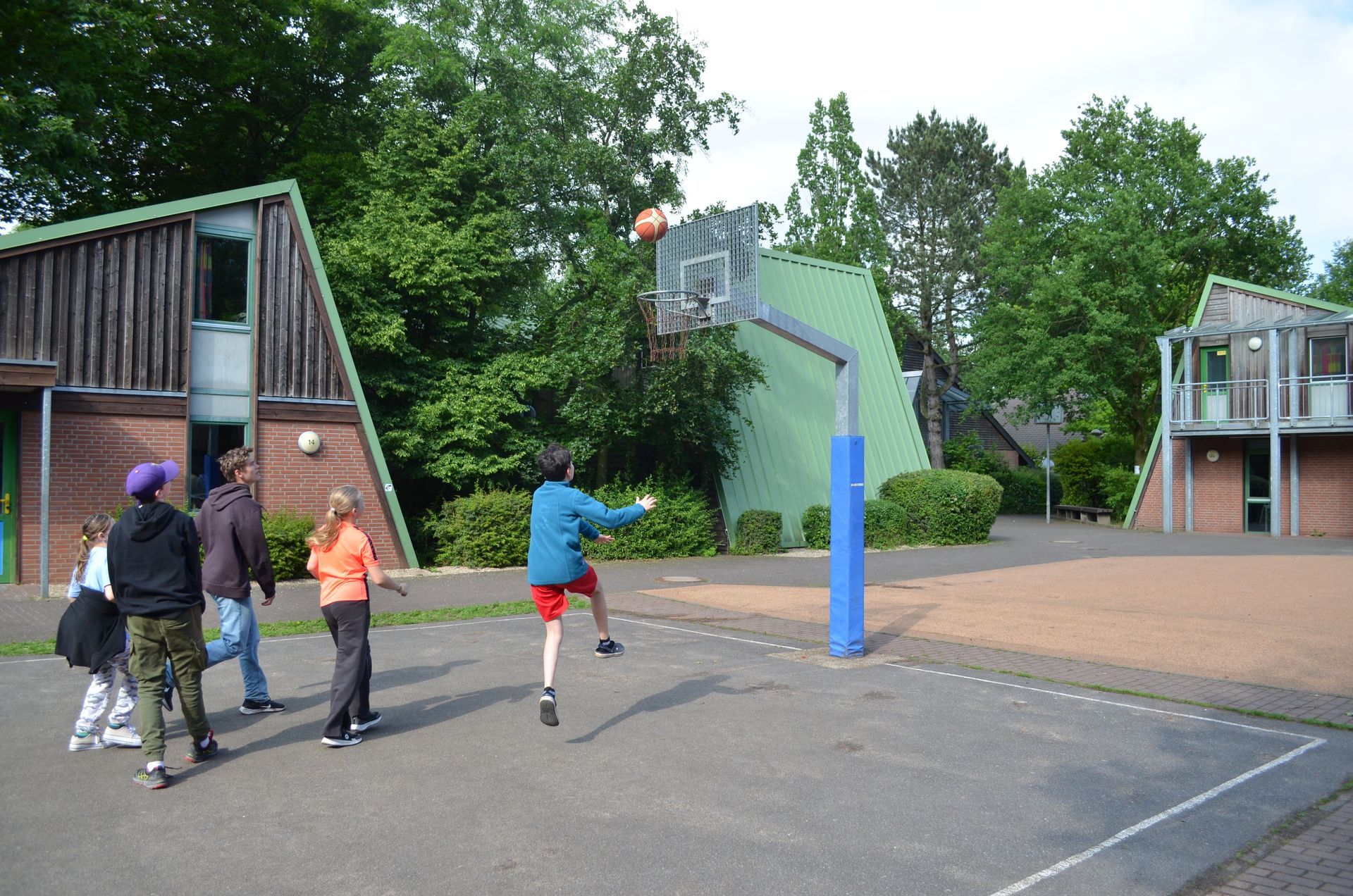 Eine Gruppe von Kindern spielt Basketball auf einem Platz - Karate-Jugendfreizeit.