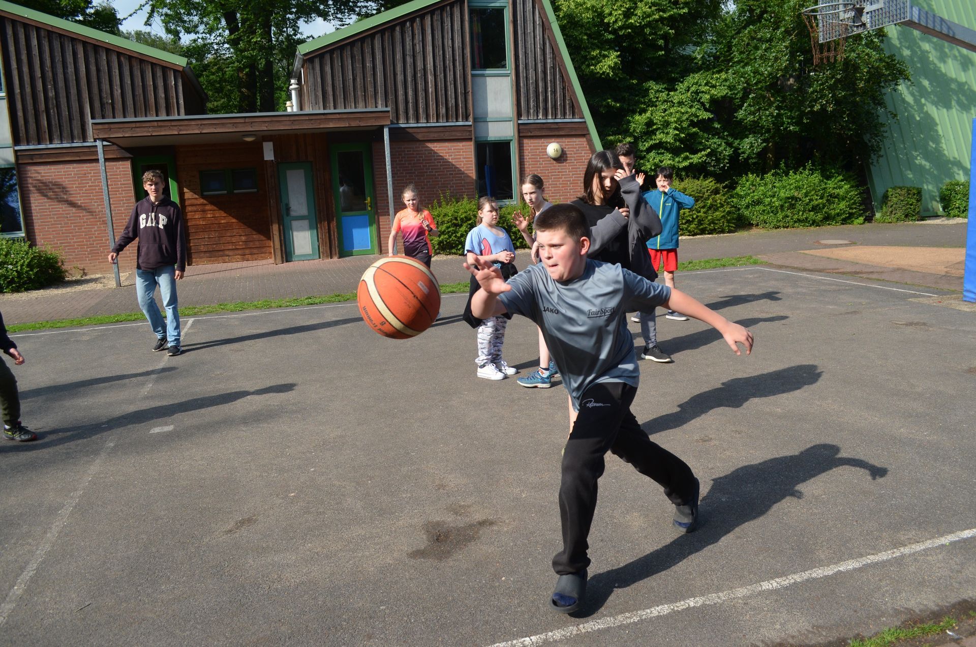 Eine Gruppe von Kindern spielt Basketball auf einem Platz - Karate-Jugendfreizeit.