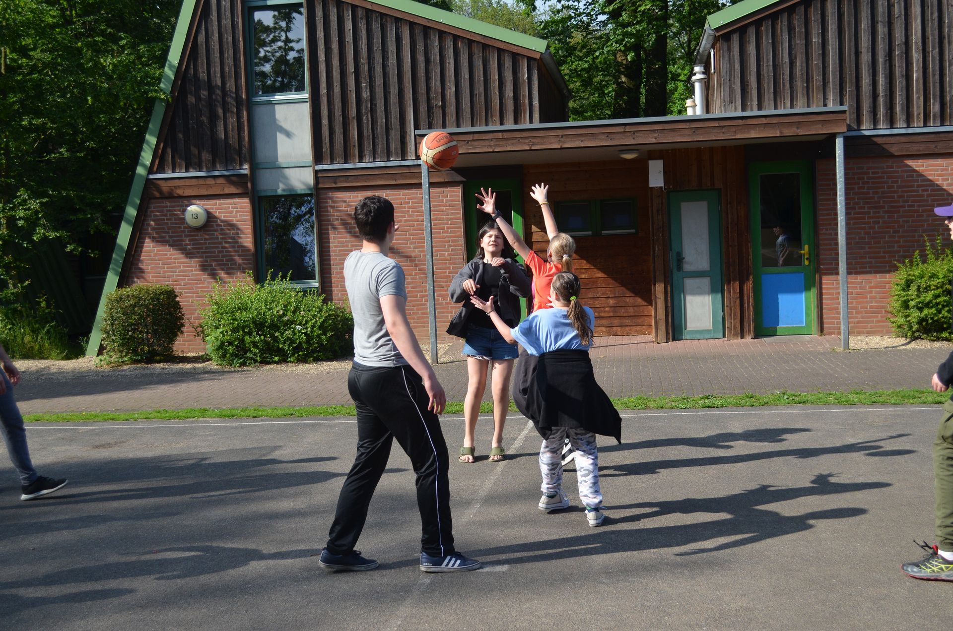 Eine Gruppe von Leuten spielt Basketball vor einem Gebäude - Karate-Jugendfreizeit.