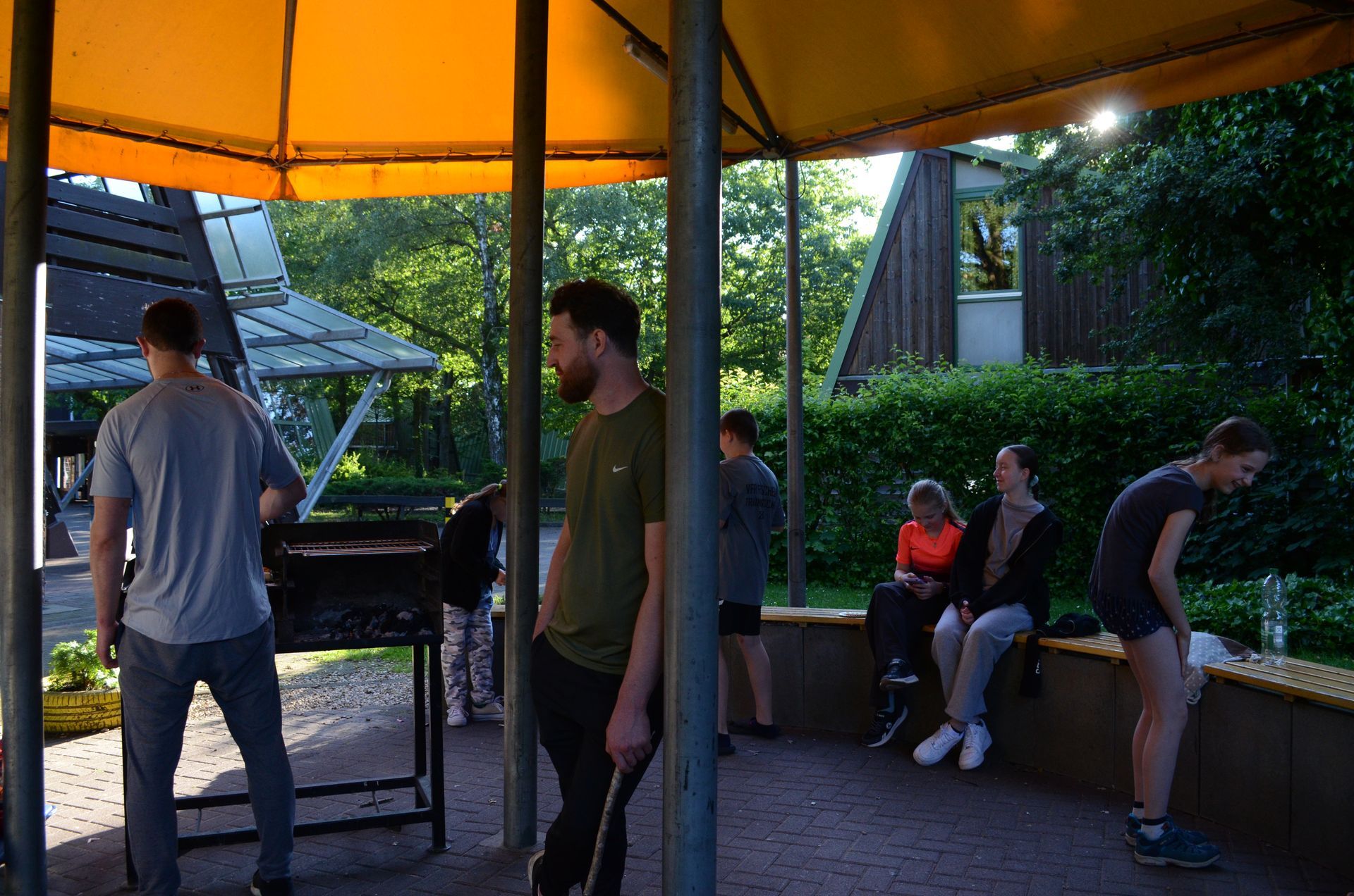 Eine Gruppe von Leuten steht und sitzt unter einem Zelt - Karate-Jugendfreizeit.