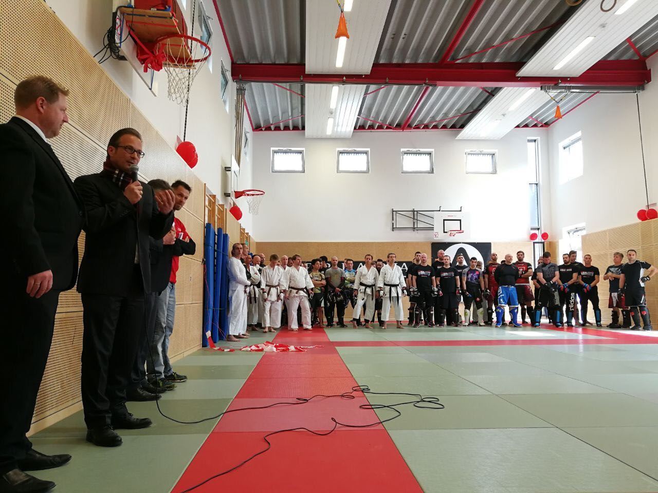 Eine Gruppe von Männern steht in einer Turnhalle und unterhält sich.