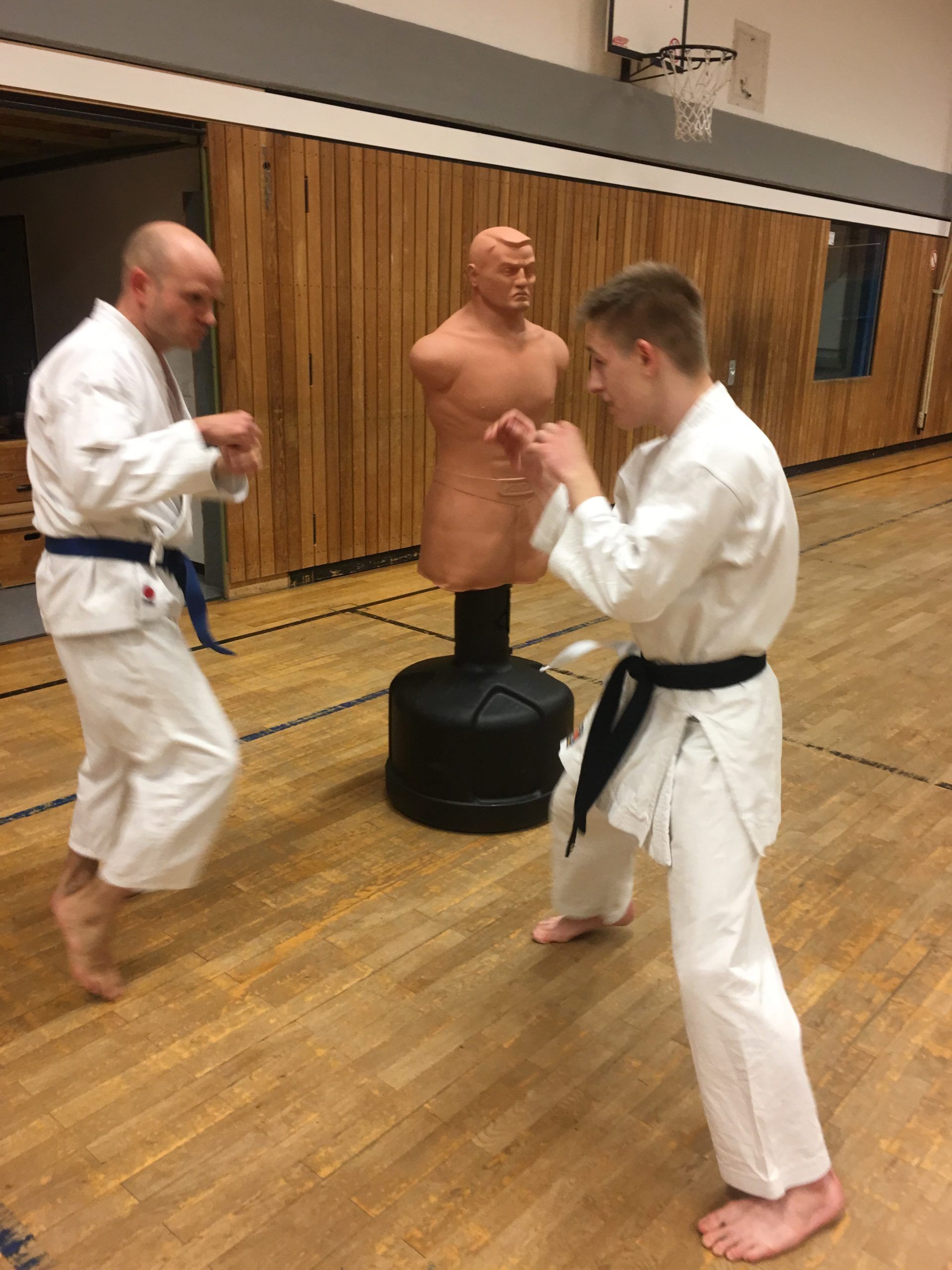 Zwei Männer in Karateuniformen üben Karate in einem Fitnessstudio.
