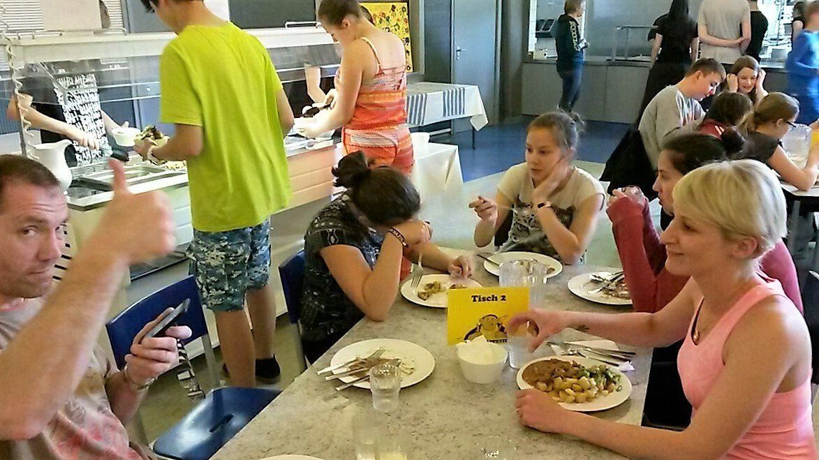 Eine Gruppe von Leuten sitzt mit Tellern voller Essen an einem Tisch.