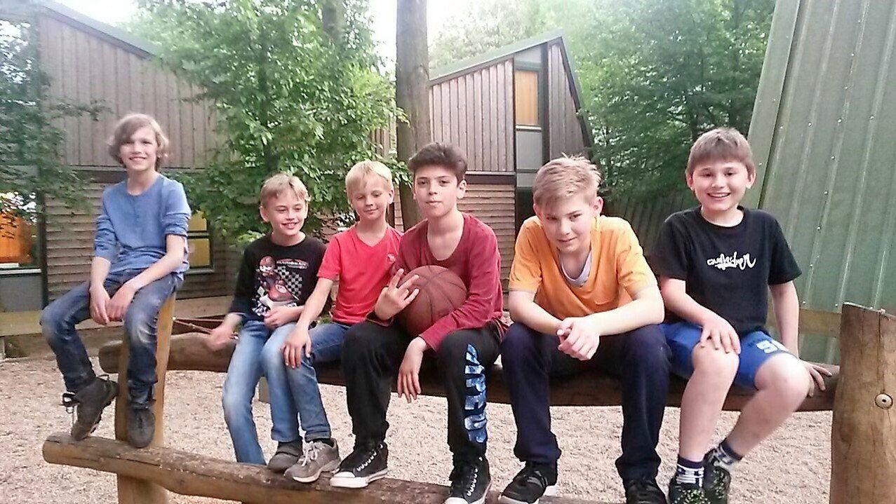 Eine Gruppe junger Jungen sitzt auf einer Holzbank.