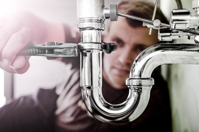 Man tightening sink pipework