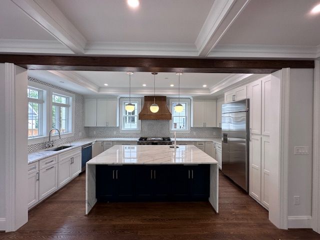 A kitchen with white cabinets and a large island in the middle