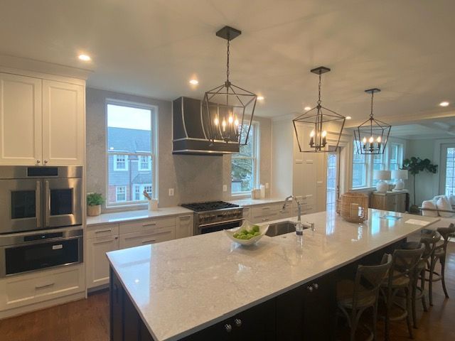 A kitchen with white cabinets , stainless steel appliances , and a large island.