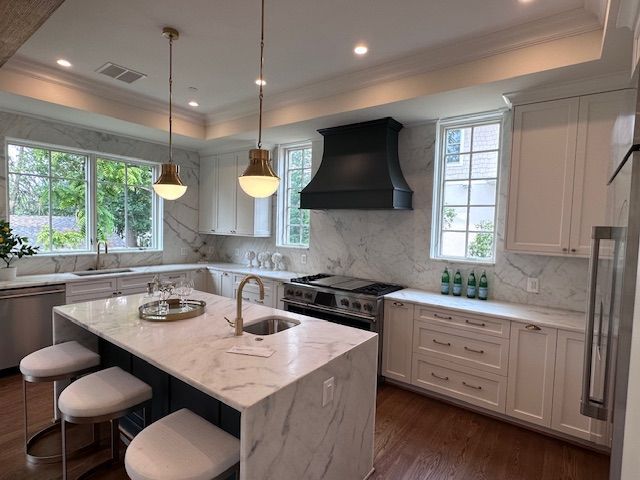 A kitchen with white cabinets and a large island in the middle.