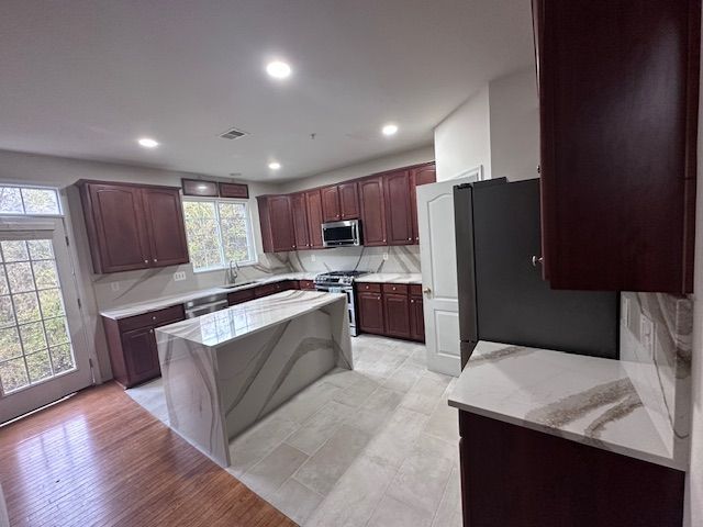 A kitchen with wooden cabinets , granite counter tops , stainless steel appliances and a large island.