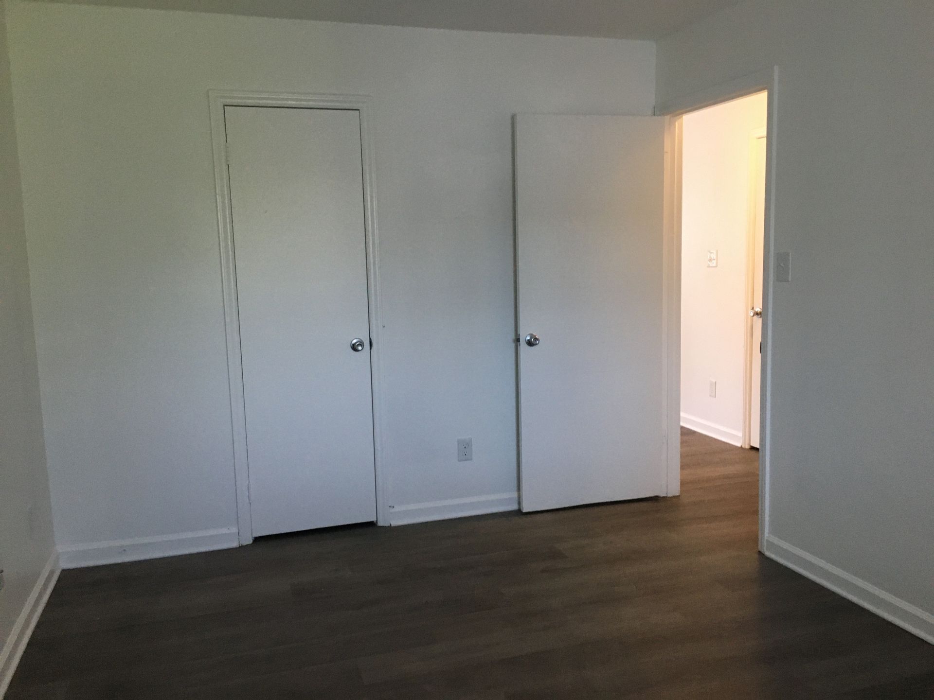 An empty bedroom with hardwood floors and white walls.