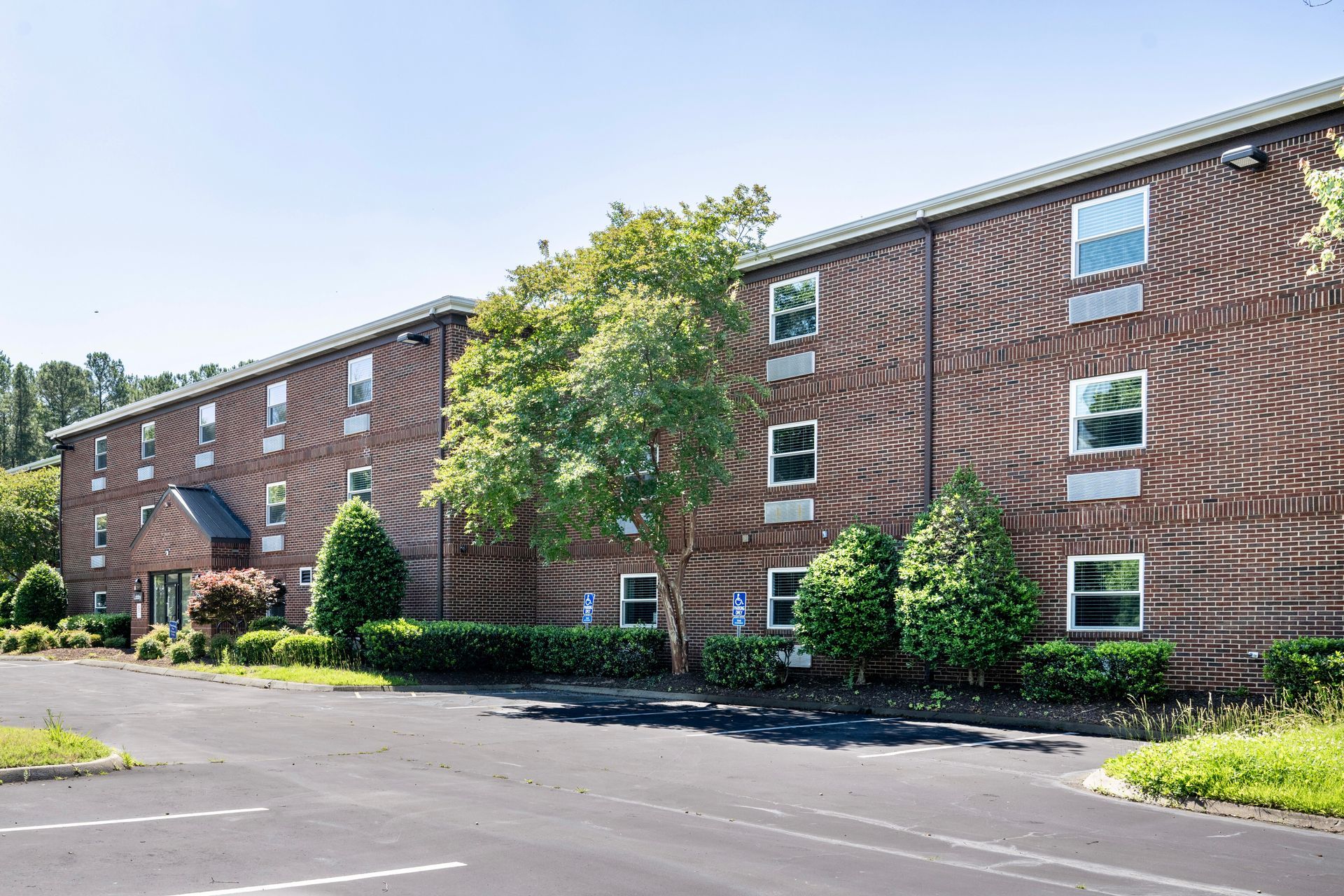 A large brick apartment building with a parking lot in front of it.