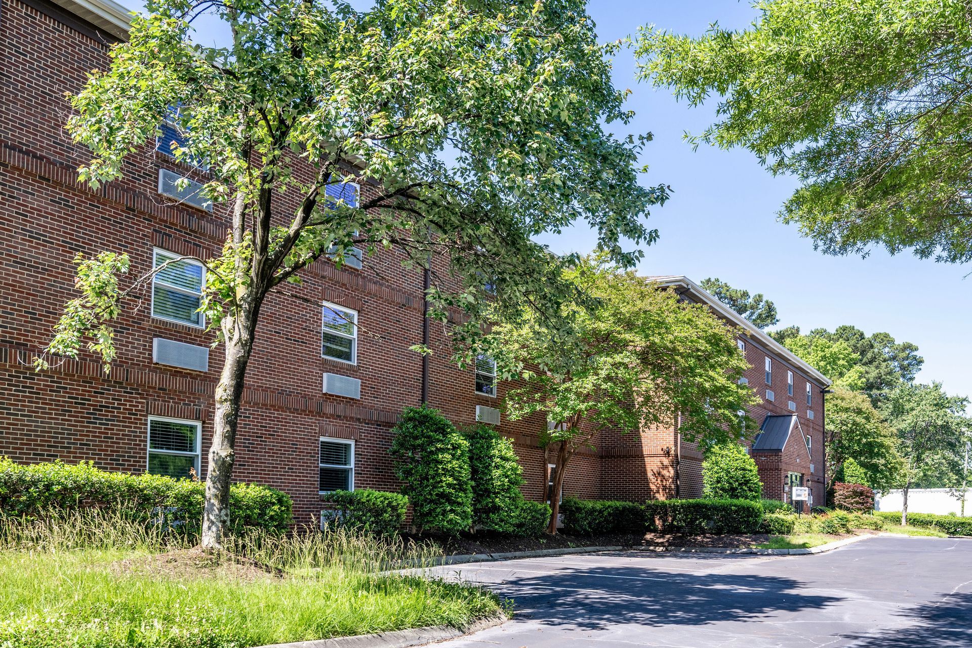 A large brick apartment building with a lot of windows and trees in front of it.