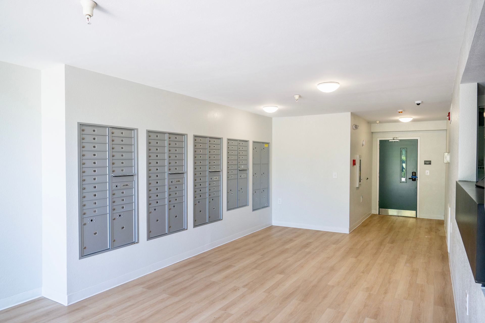 An empty hallway with a row of mailboxes on the wall