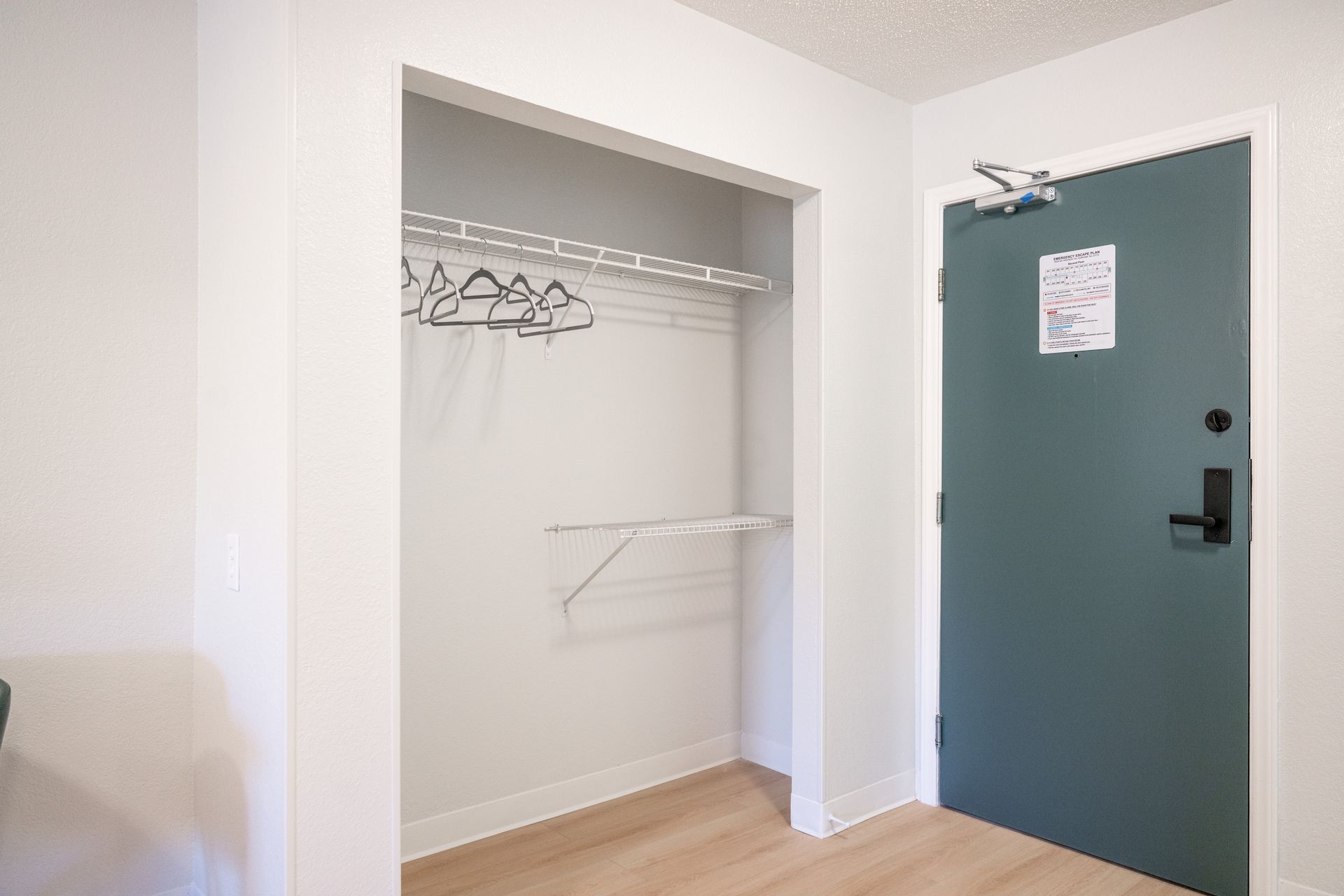 A walk in closet in a room with a blue door.