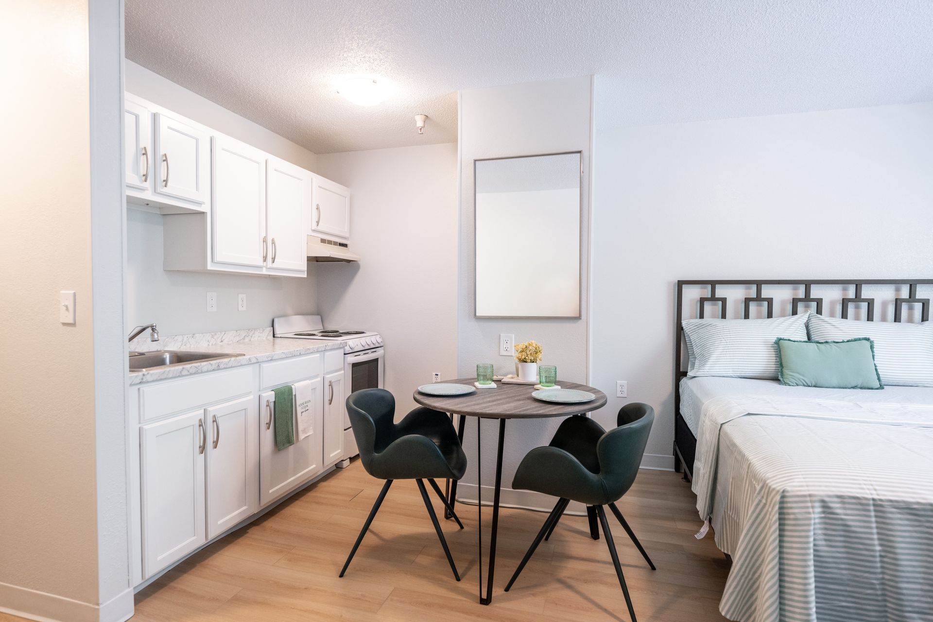 A studio apartment with a bed , table , chairs and a kitchen.