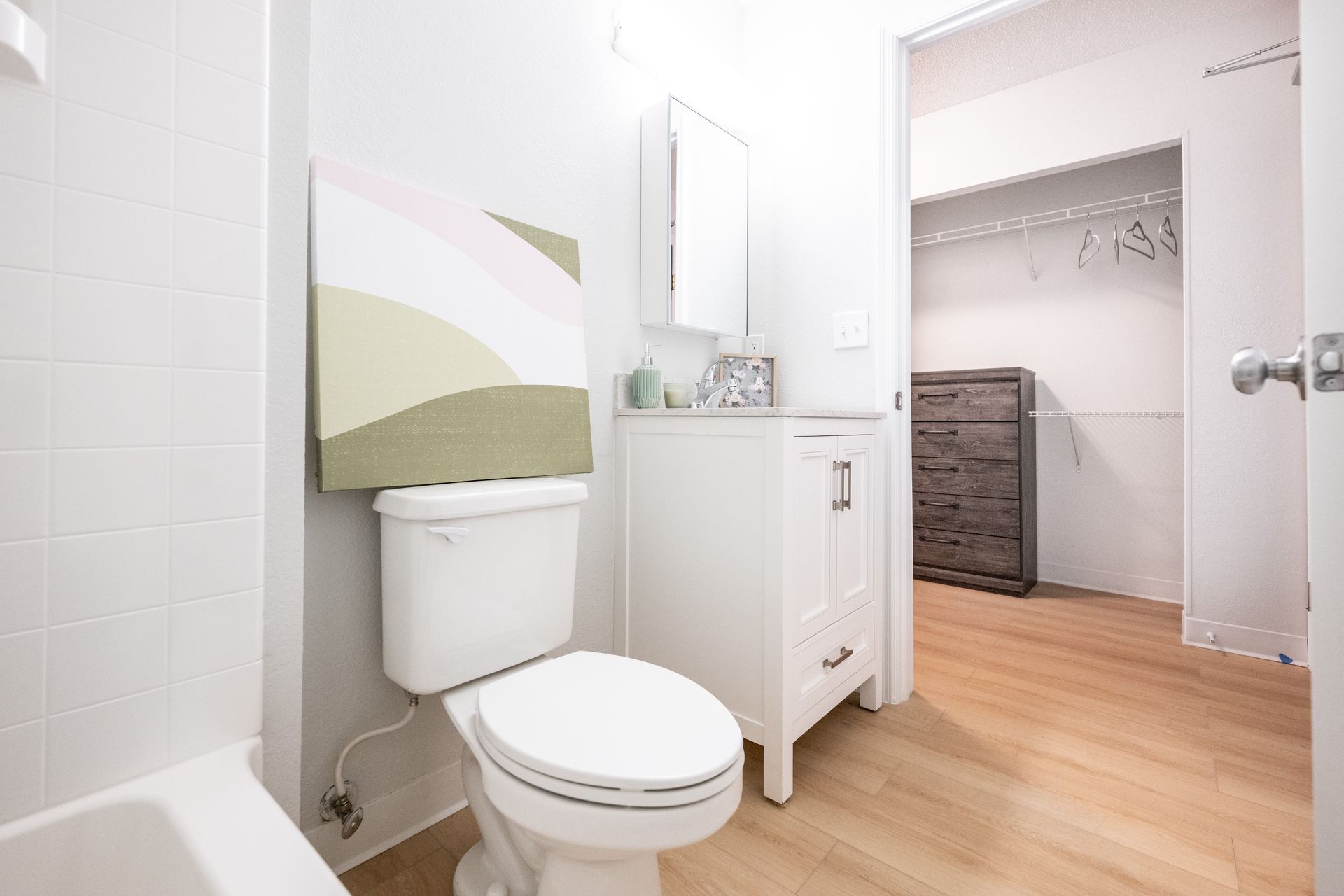 A bathroom with a toilet , sink , and walk in closet.