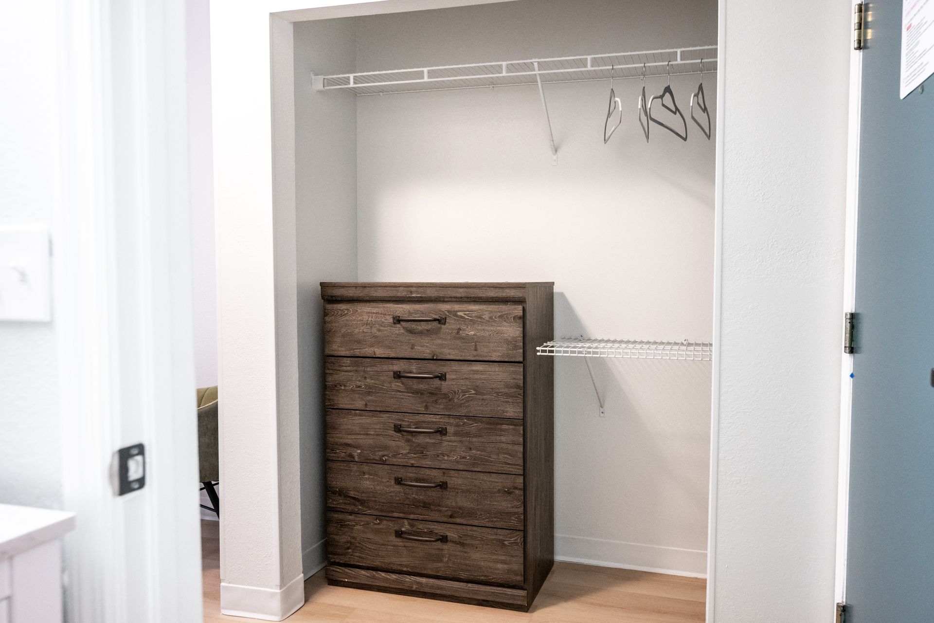 A walk in closet with a dresser and clothes racks.