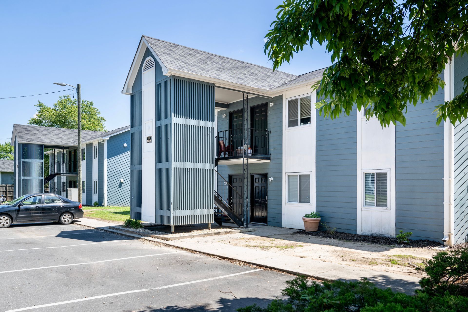A blue and white apartment building with a car parked in front of it.