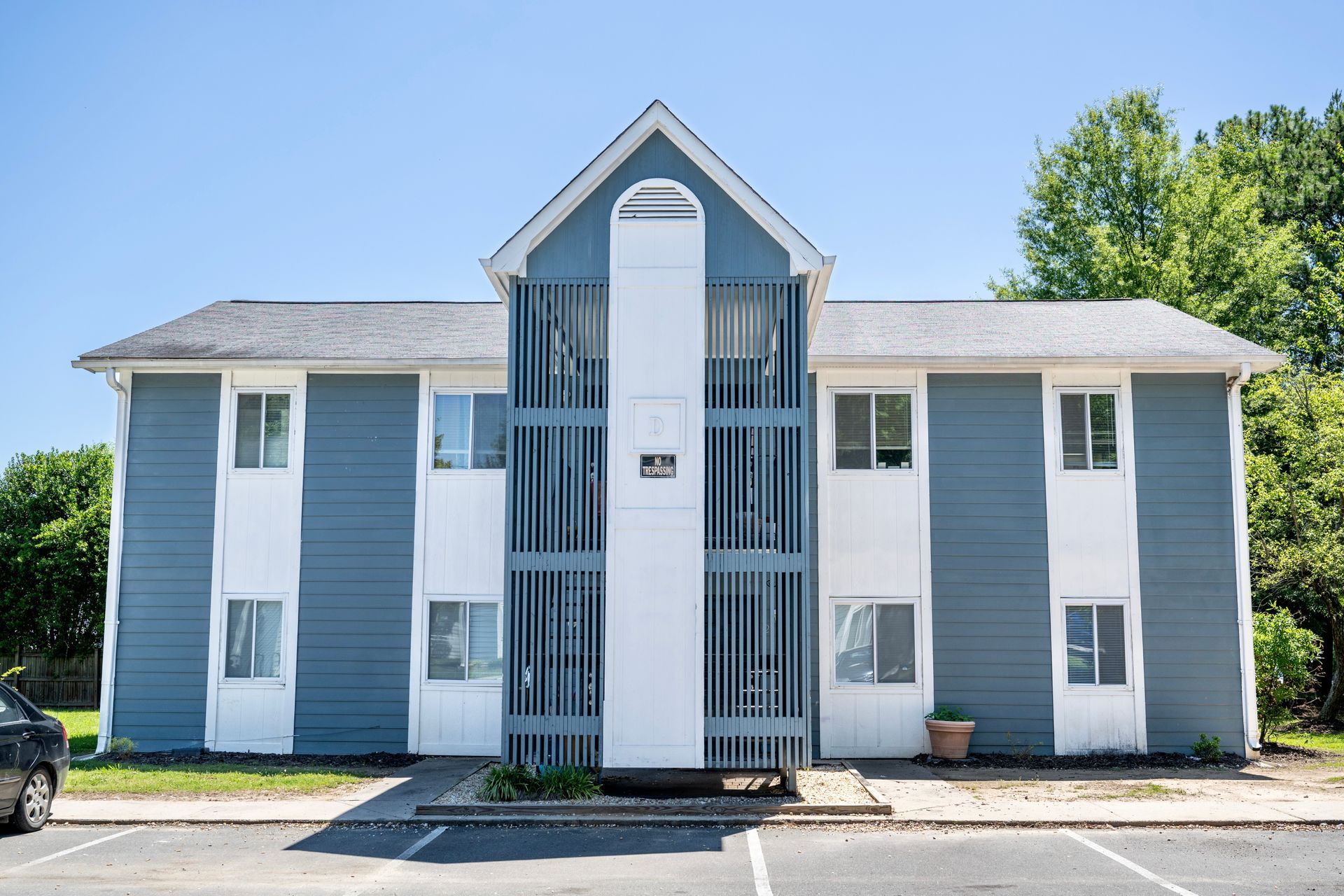 A blue and white apartment building with a car parked in front of it