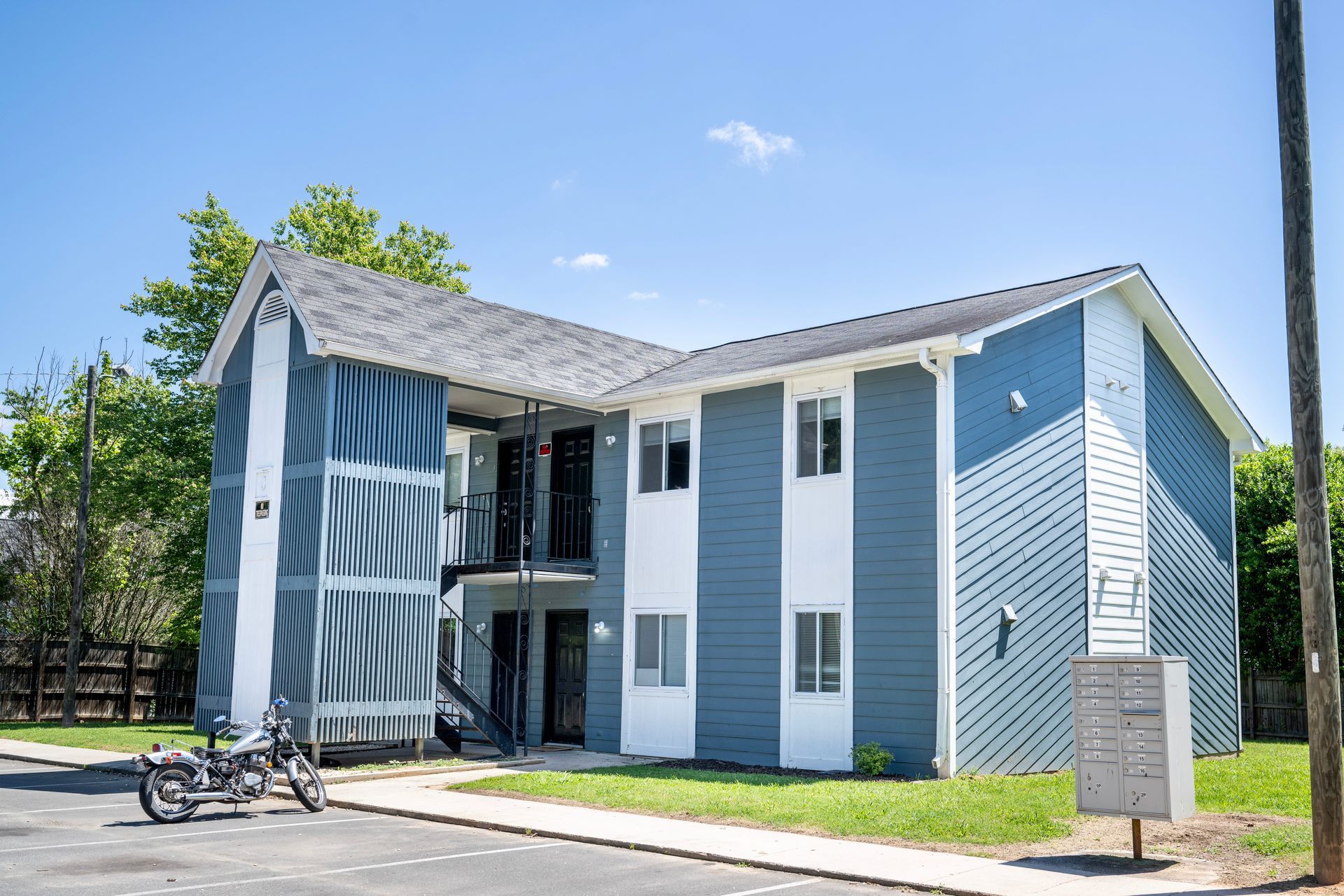 A blue and white apartment building with a motorcycle parked in front of it.