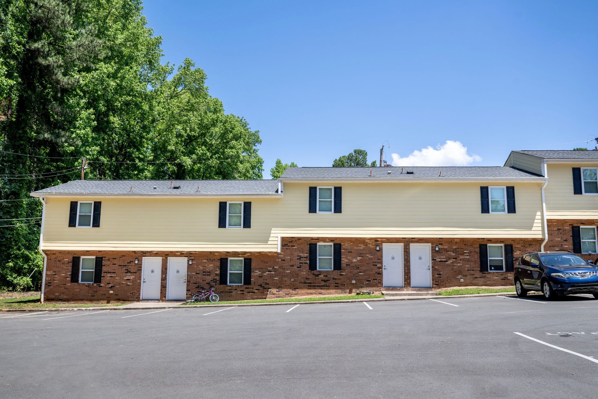 A row of apartment buildings with cars parked in front of them.