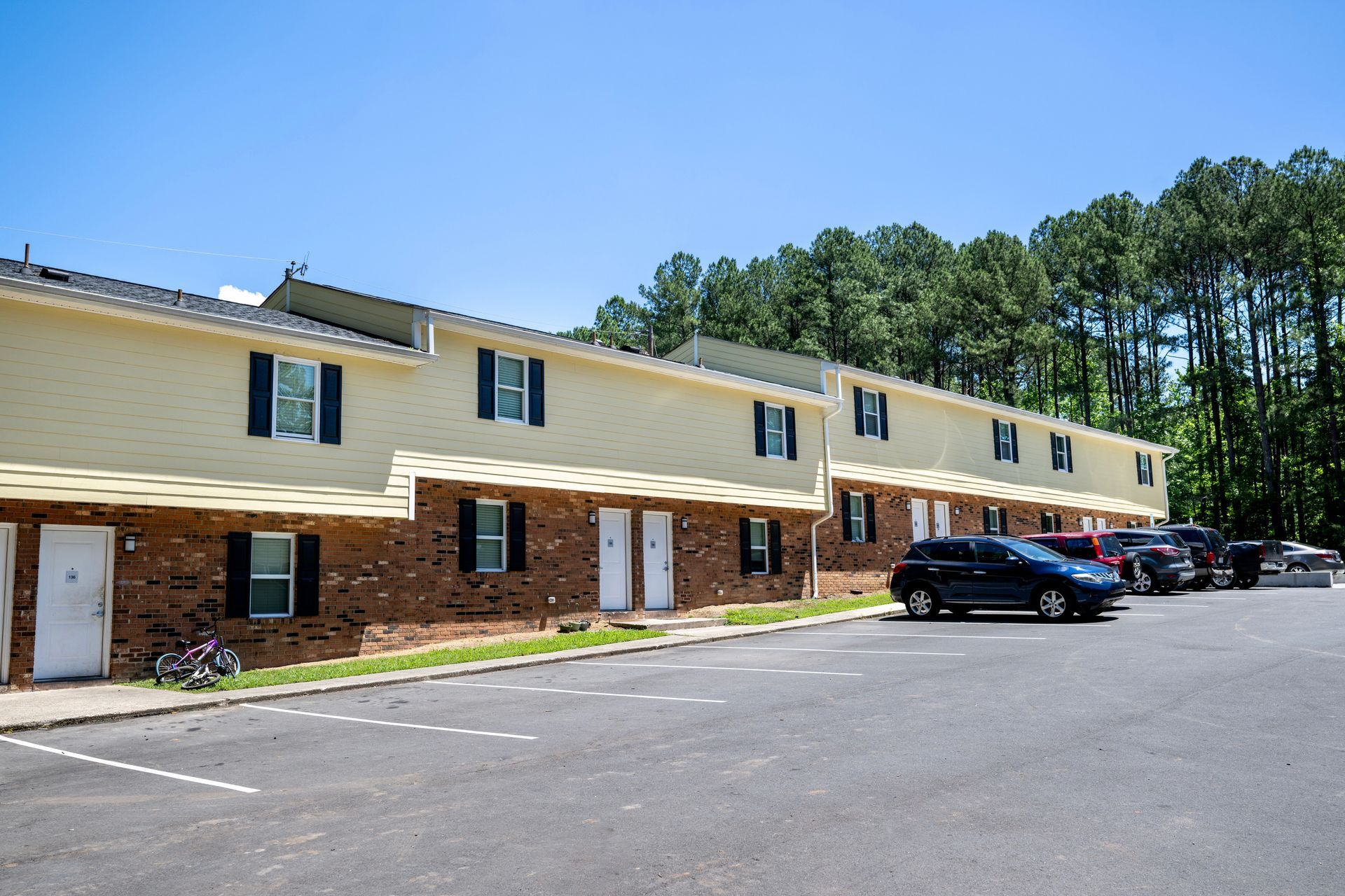 A row of apartment buildings with cars parked in front of them