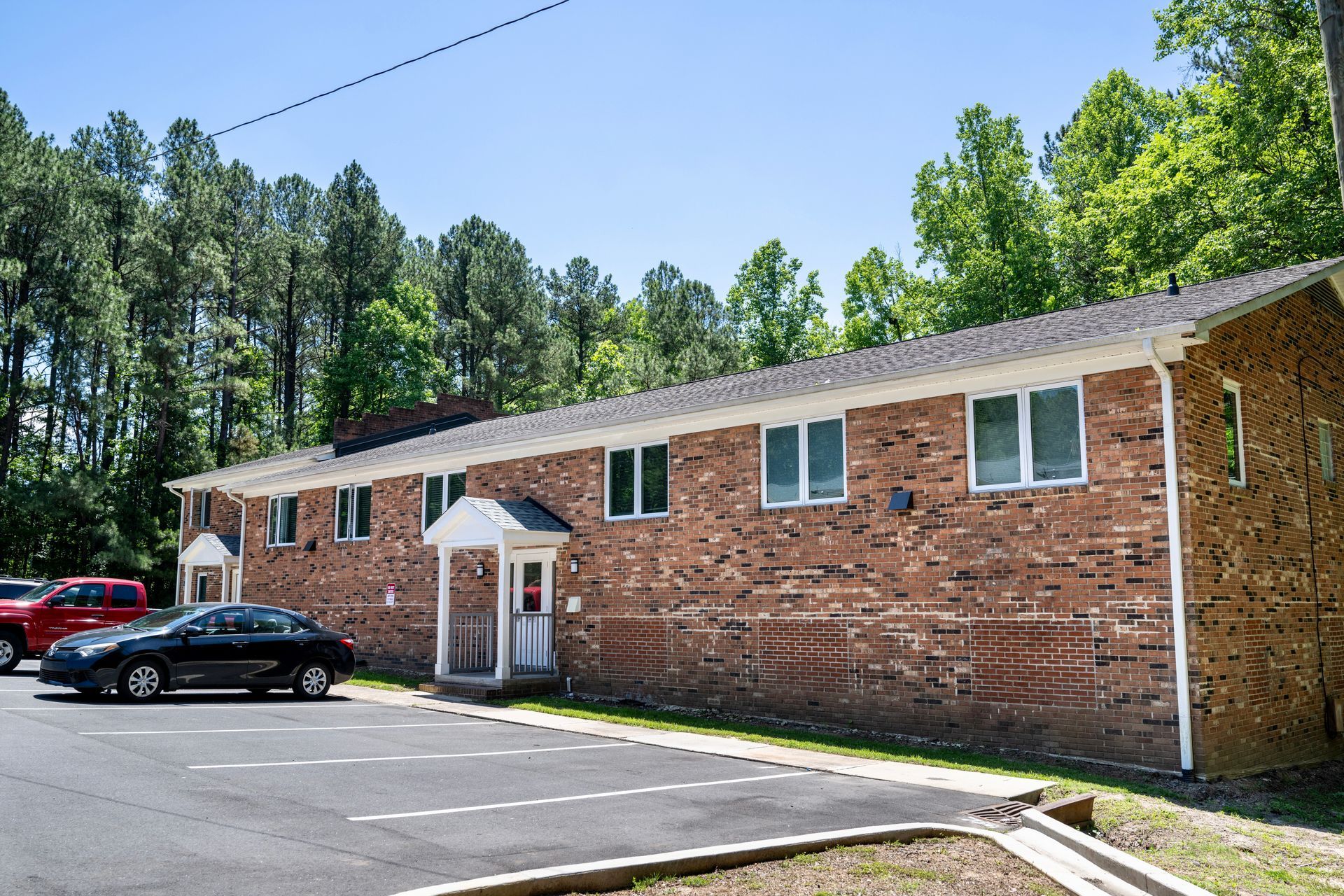A black car is parked in front of a brick building