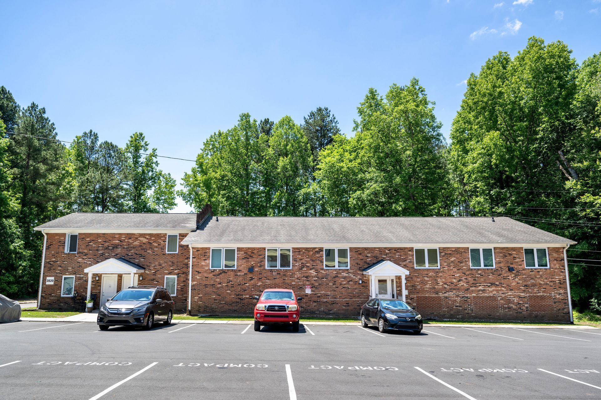 Three cars are parked in front of a brick building