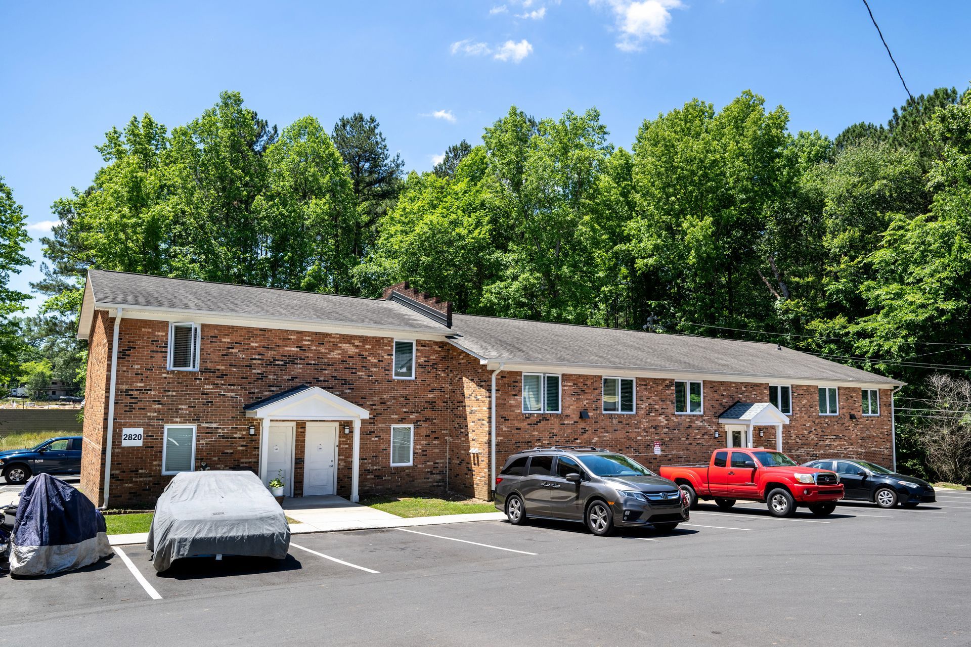 A row of cars are parked in front of a brick building