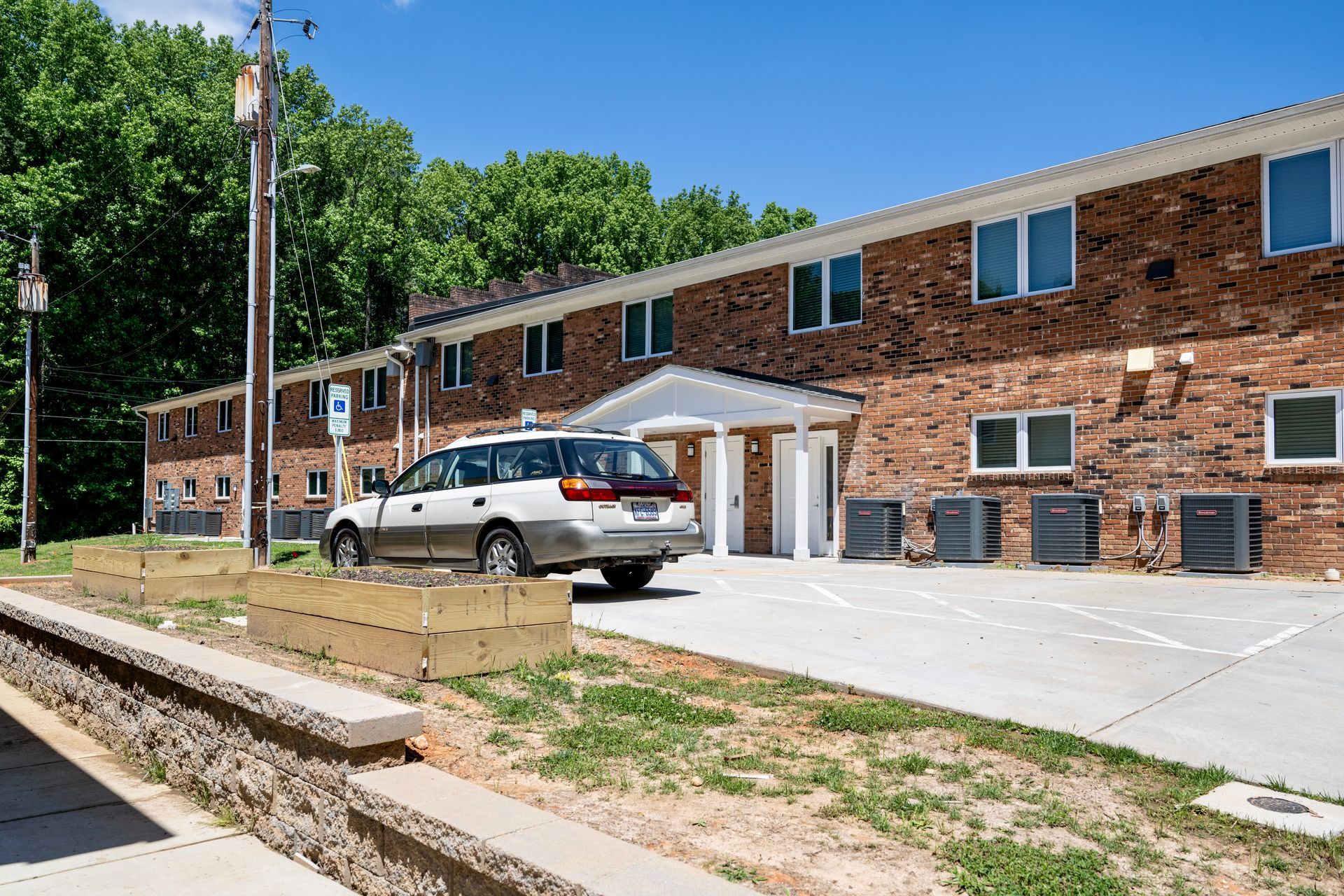 A white van is parked in front of a brick apartment building.