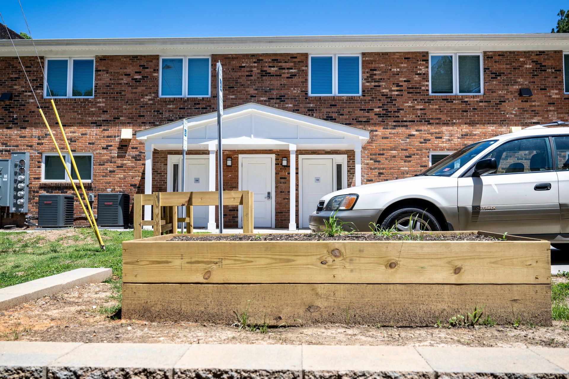 A car is parked in front of a brick apartment building.