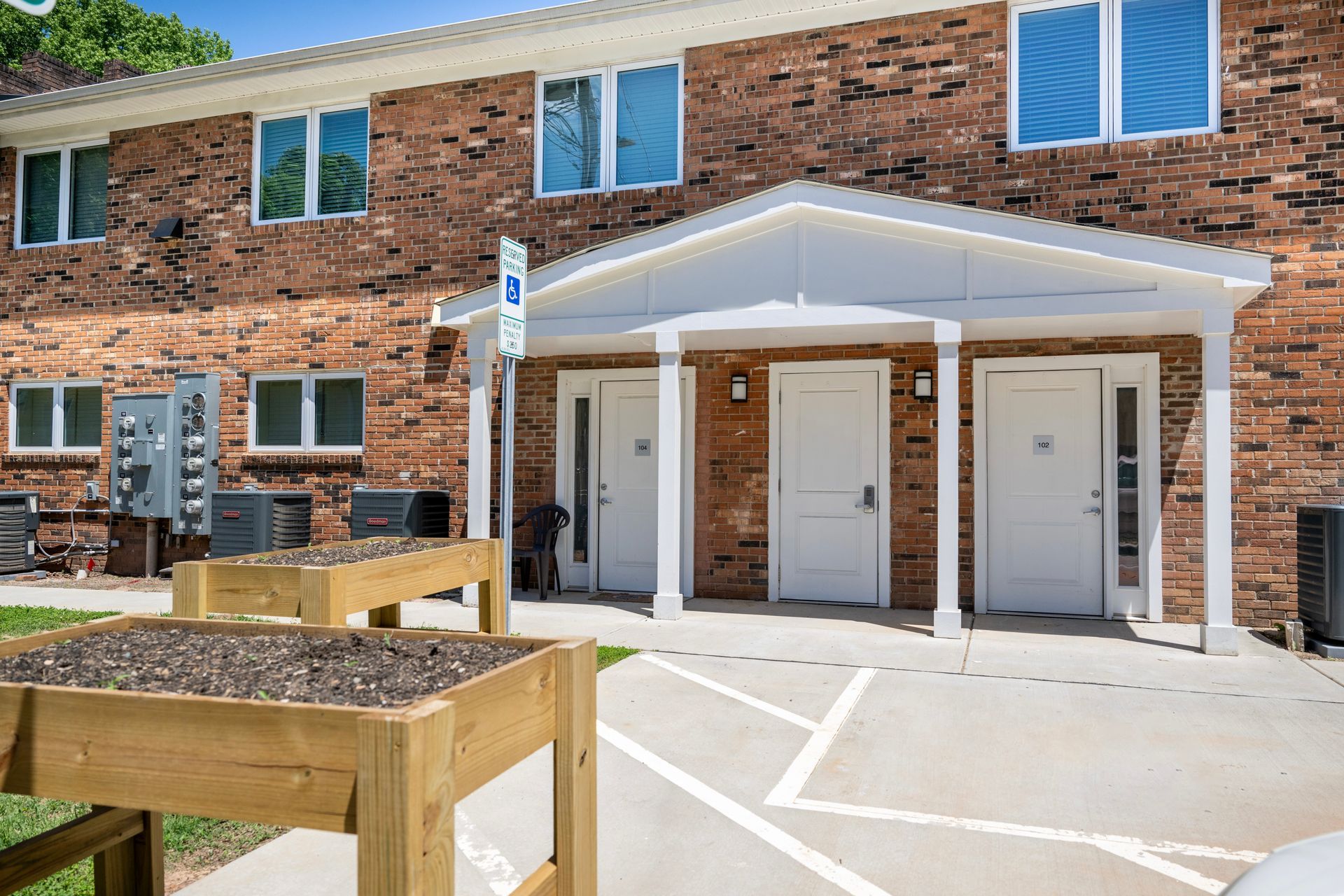 A brick apartment building with a wooden planter in front of it.